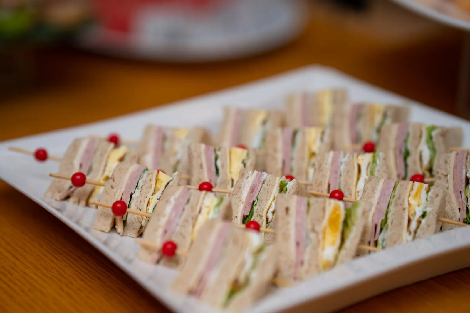Charola de sándwiches pequeños cortados en triángulo para un coffee break