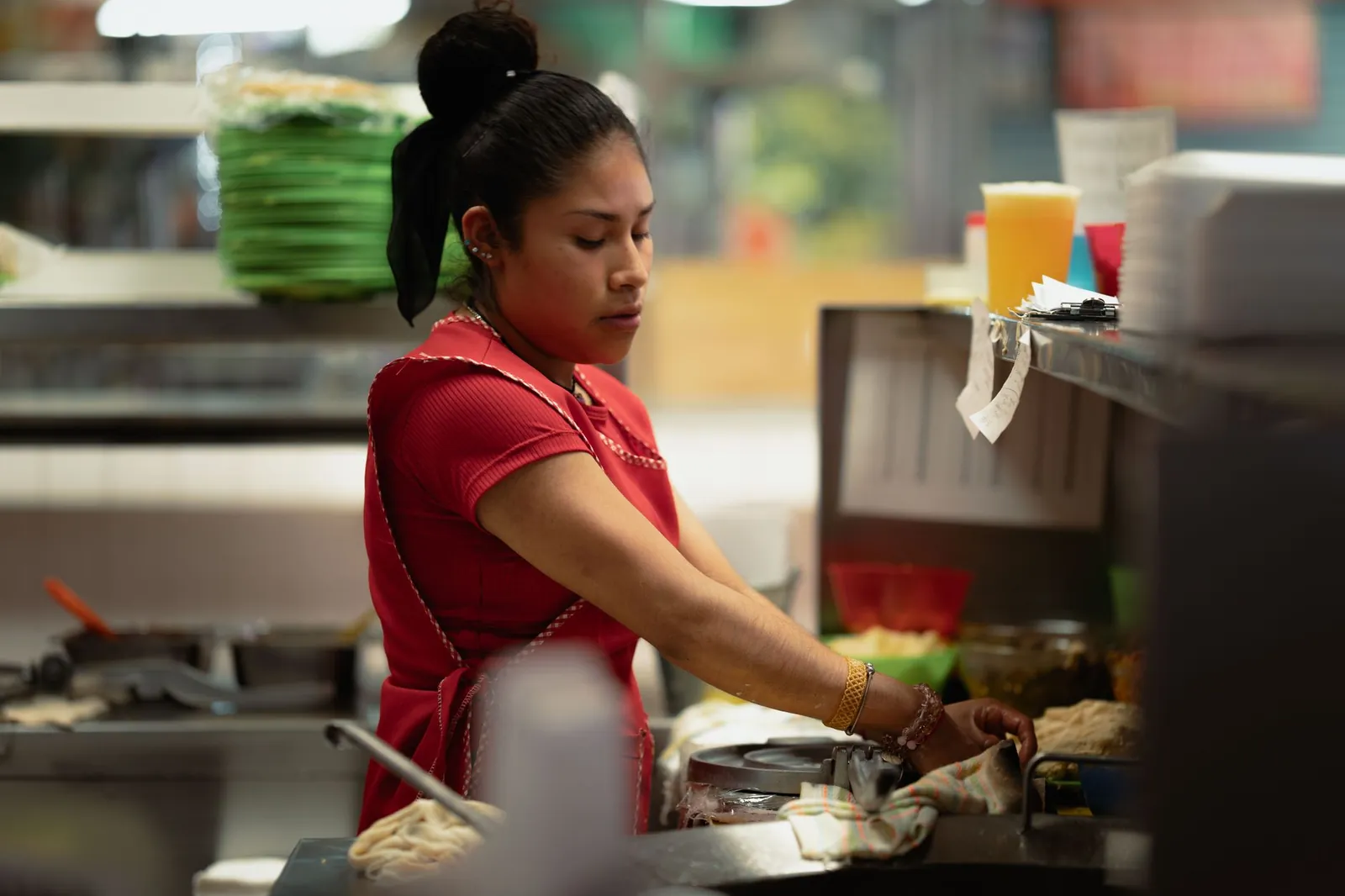 Cocinera preparando alimentos en la estación de una cocina profesional