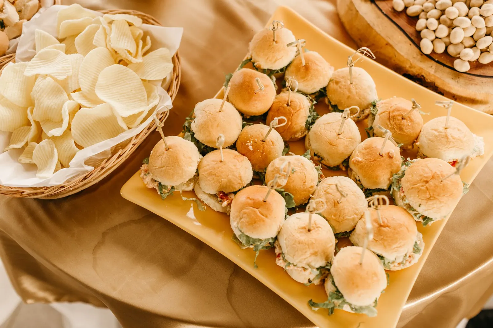 Mini hamburguesas en charola junto a una canasta de papas para coffee break