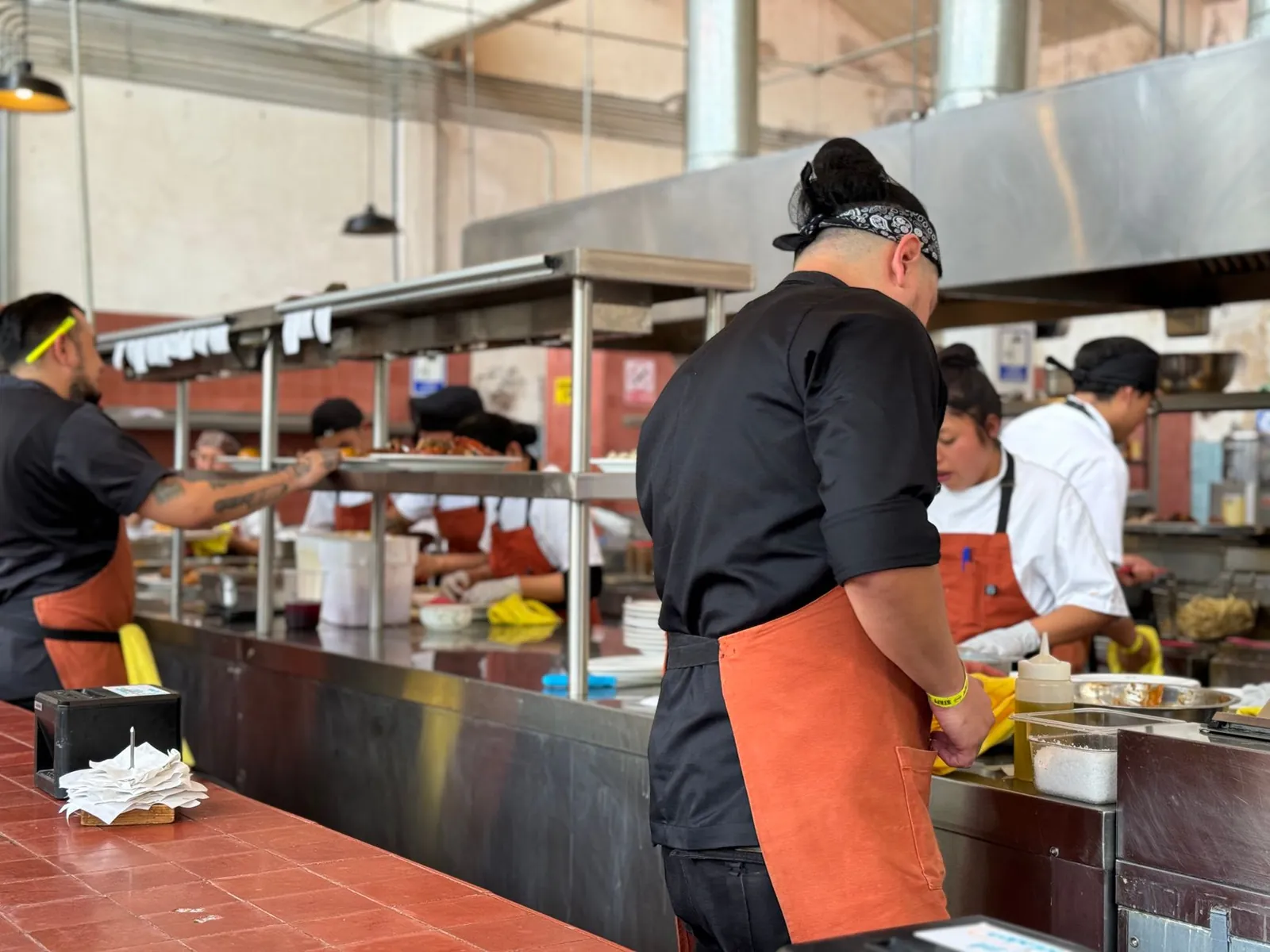 Cocineros trabajando en la línea de una cocina industrial de acero inoxidable